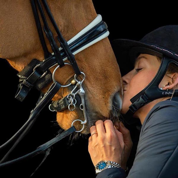 Catherine Dufour dando un beso a un caballo marrón