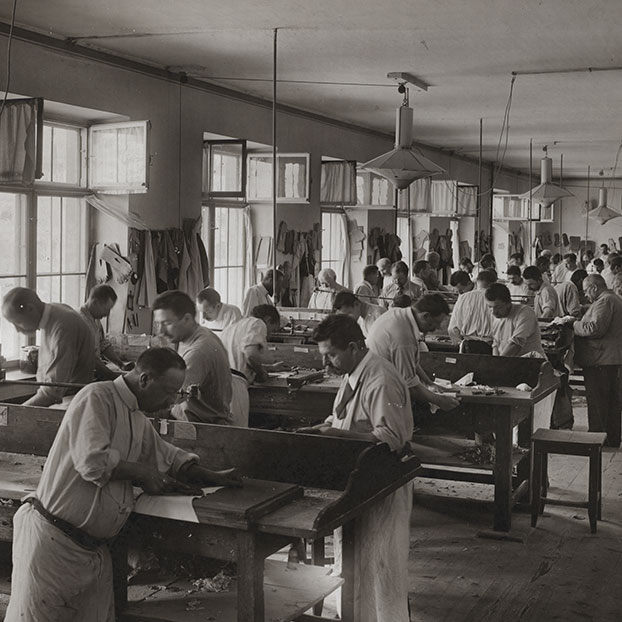 Una foto en blanco y negro del taller Roeckl en Austria. Los trabajadores estan creando guantes de equitación y otros deportes.